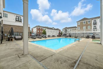 A large outdoor swimming pool surrounded by a fence and buildings.